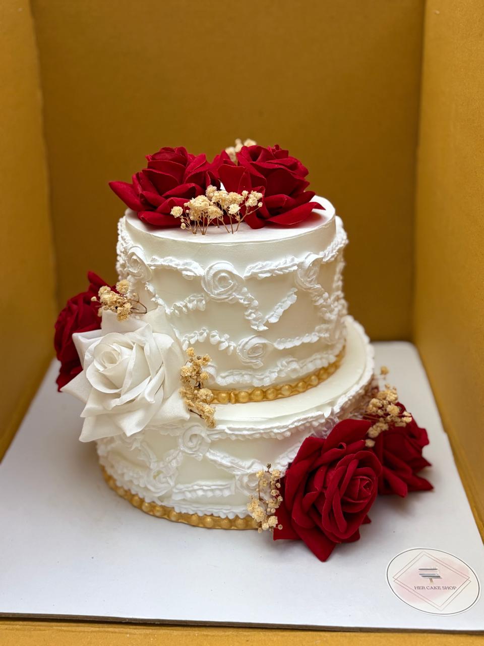 Two-tier white cake with red roses and gold trim