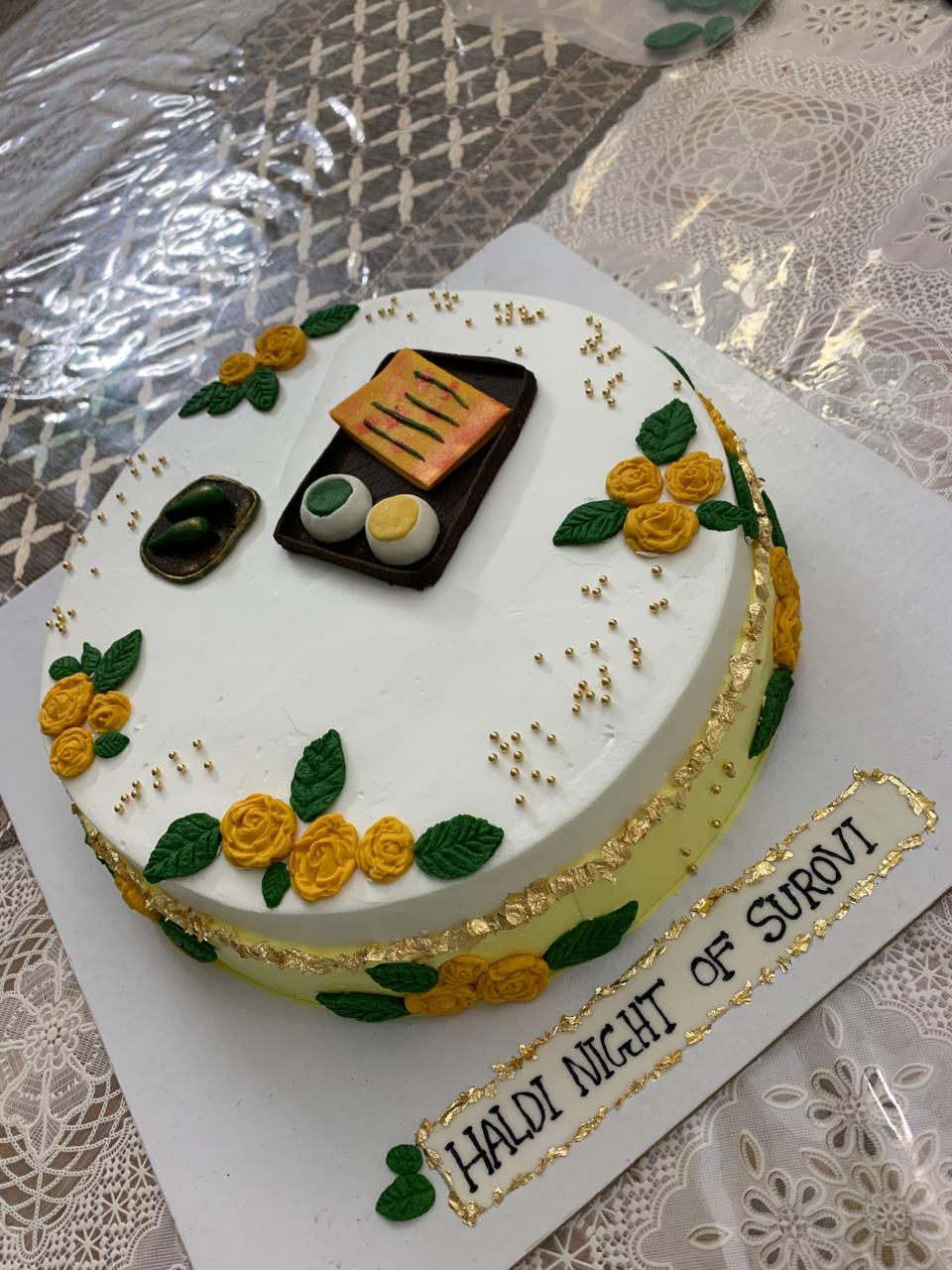 Haldi themed cake with yellow roses and gold leaf